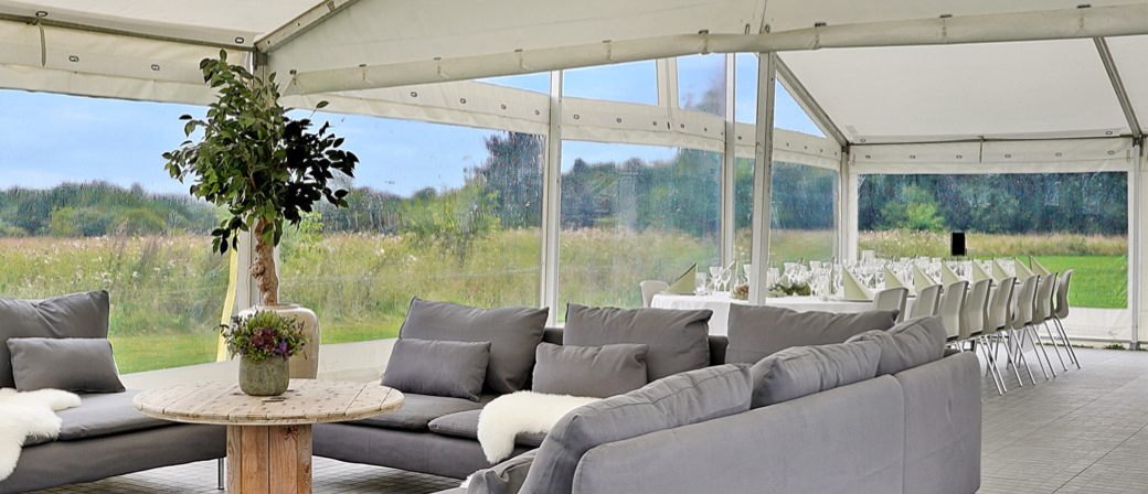 Lounge med grå sofaer og lysekrone i teltet